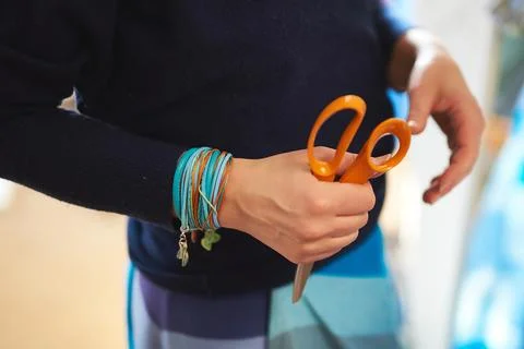 Midsection view of a tailor holding orange craft scissors in a fashion design 写真素材