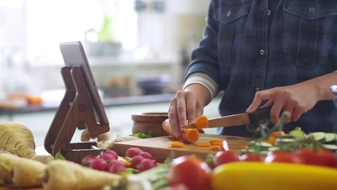 Midsection of woman cutting carrot while using digital tablet Stock Footage 70073149