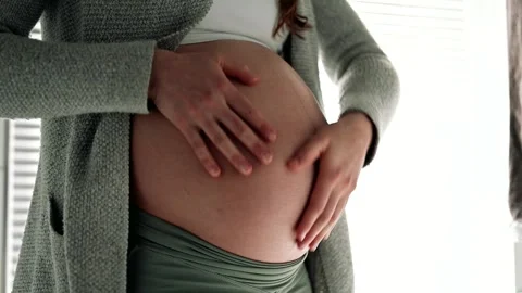 Midsection of woman gently caressing her round belly in lsdt month of pregnancy. Stock Footage 243508152