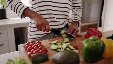 Midsection of woman standing by kitchen table cutting fresh zucchini with knife Stock Footage 140498124