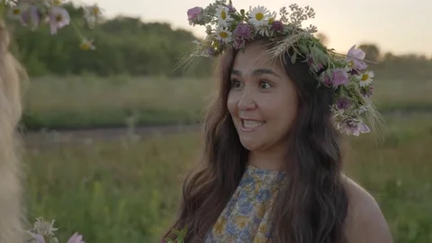 Midsummer. Two girls are talking and weaving wreaths in the field. Video stock 205404953