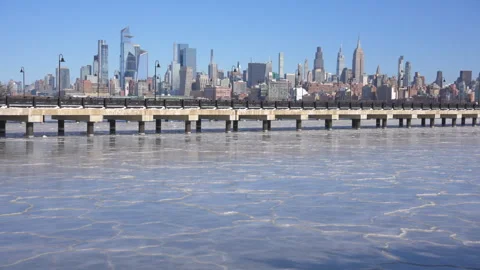 Midtown Manhattan skyscraper stands beyond frozen Hudson River from New Jersey Vídeo Stock 336632121