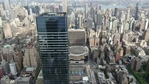 Midtown office tower rises above dense Manhattan blocks and arena roof Vídeo Stock 130999338