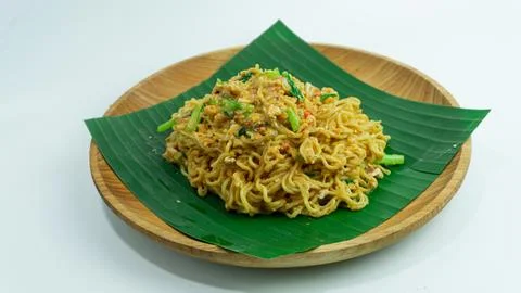 Mie Nyemek. Fried noodles served on a wooden plate covered with banana leav.. Stock Photos
