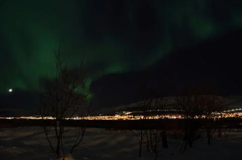 Mighty northern light dancing over snowy mountain peak in northern norway o.. Stock Photos