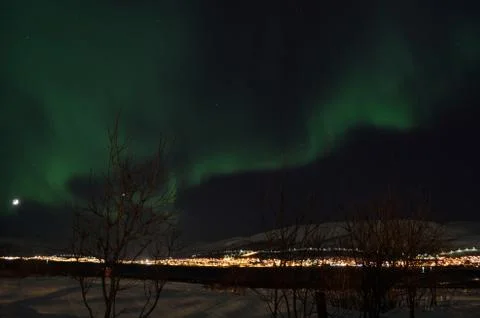Mighty northern light dancing over snowy mountain peak in northern norway o.. Stock Photos