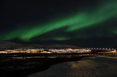 Mighty northern light dancing over snowy mountain peak in northern norway o.. Stock Photos