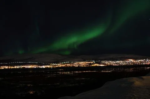 Mighty northern light dancing over snowy mountain peak in northern norway o.. Stock Photos