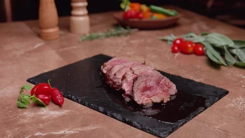 Mignon steak on a marble table with tomatoes and fresh green herbs and peppers Stock Footage