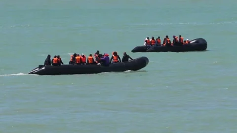Migrant taxi boat shadowed by the Cliffs d'Ault in northern France Stock Footage 336912497