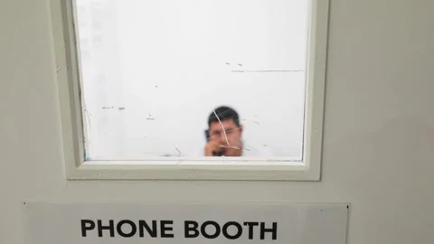 Migrant using telephone in booth at Customs Border Protection Processing Center Stock Footage 269902467