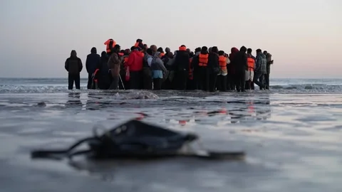 Migrants board a dinghy on Dunkirk beach during a Channel crossing attemp... Stock Footage 332336658
