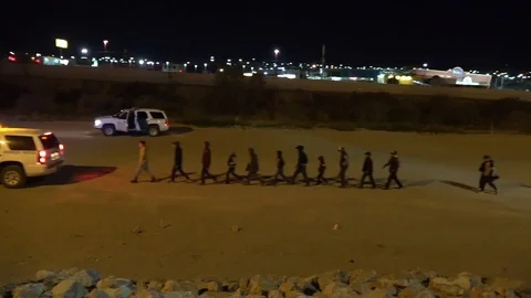 Migrants escorted by border patrol vehicles at southwest border at night Stock Footage 106117201