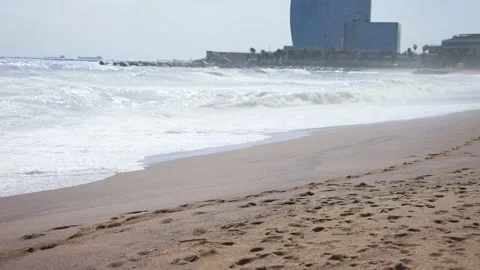 Mild waves on a beach with buildings in the background - Slow Motion Stock Footage 173767348