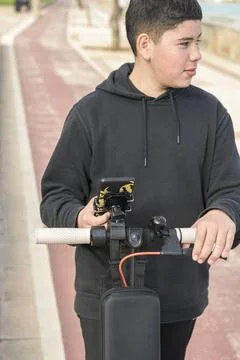 Milenian joven con patinete eléctrico un smartphone Stock Photos