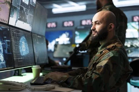 Military analyst studying digital data interface at workstation Stock Photos