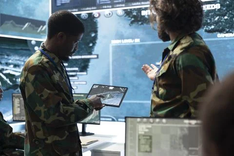 Military analysts looking at map on tablet screen and doing brainstorming Stock Photos
