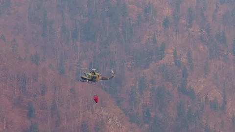 Military chopper with a specialized empty bucket flying Stock Footage 176482328