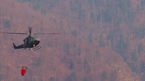 Military helicopter with a specialized empty bucket descending Stock Footage 176484103