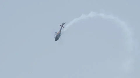 Military helicopter upside down diving maneuver drawing smoke arc in sky Stock Footage 340135012