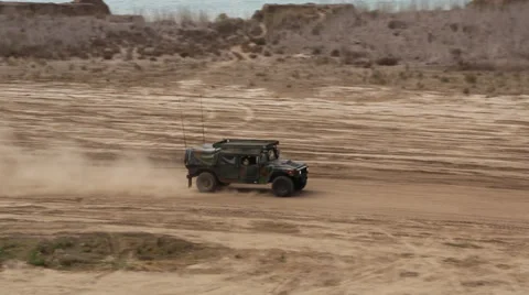 Military humvee passes left to right across desert floor Stock Footage