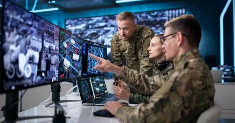 Military Intelligence Team Using Computers In Office To Monitor Missions. Foto stock