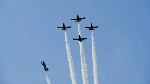 Military jet makes loop around other planes at airshow, releasing smoke strips. Stock Footage 120592863