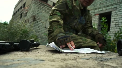 A military man examines a map of the area and smokes a cigarette Stock Footage 166361352