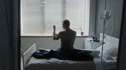 Military Man Sitting on Bed Examining Bandaged Arm in Hospital Ward Stock Footage 340627448