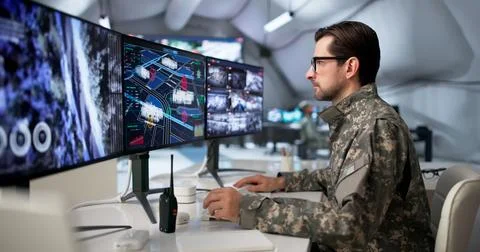 Military Officer Studies Data On Computer Desk In Secure Intelligence Center. Stock Photos