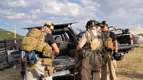 Before the military operation.Armed men gather things from the trunk of the jeep Stock Footage 129459355