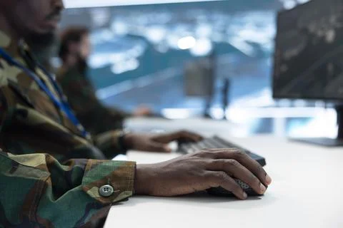 Military operator uses mouse at computer desk to track enemy movements Stock Photos