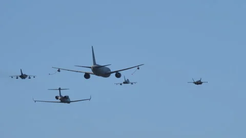 Military planes fly in formation simulating air refueling from a tanker Video stock 164390772