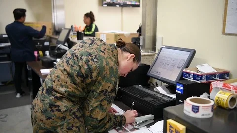 Military postal worker completing amd stamping paperwork Stock Footage 122210651