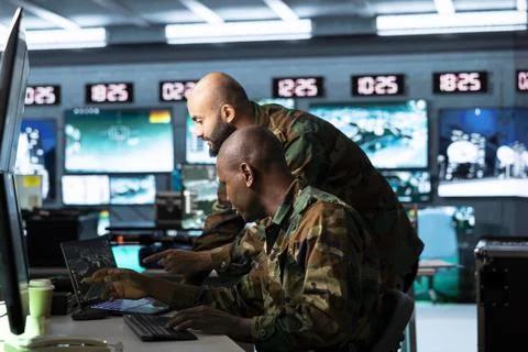 Military team working together in command post on laptop Stock Photos
