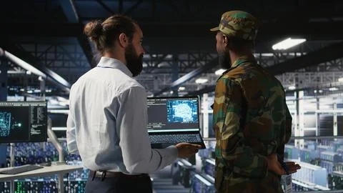 Military technicians in secure data center use laptop to monitor AI systems Foto stock