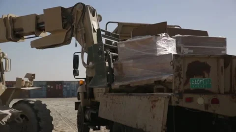 Military telescopic handler loads pallet of boxes onto truck at Al Asad Air Base Stock Footage 168740767