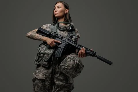 Military woman with brown hairs and rifle against dark background Stock Photos