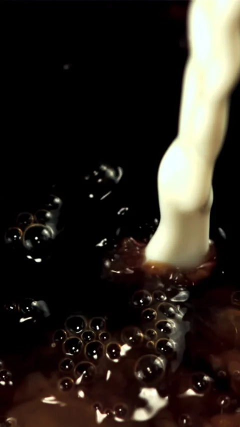 Milk with air bubbles is poured into black coffee. Filmed is slow motion 1000 Stock Footage 335286478