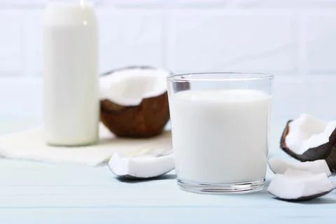 Milk and broken coconuts on the table. Vegetable milk, a veggie drink. Stockfoto's