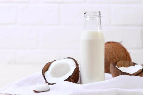 Milk and broken coconuts on the table. Vegetable milk, a veggie drink. Stock-Fotos