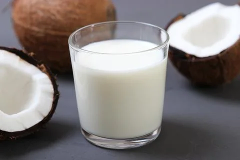 Milk and broken coconuts on the table. Vegetable milk, a veggie drink. Stockfoto's
