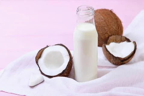 Milk and broken coconuts on the table. Vegetable milk, a veggie drink. Stock-Fotos