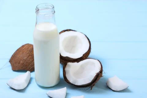Milk and broken coconuts on the table. Vegetable milk, a veggie drink. Stock Photos
