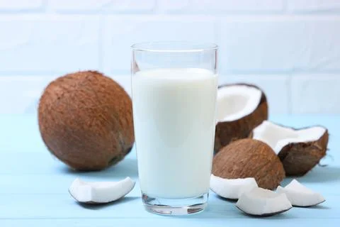 Milk and broken coconuts on the table. Vegetable milk, a veggie drink. Stock Photos