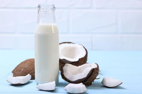 Milk and broken coconuts on the table. Vegetable milk, a veggie drink. Stock Photos