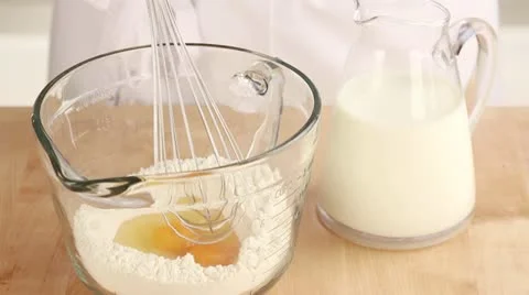 Milk being added to flour and a beaten egg Stock Footage 24671748