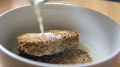 Milk being poured over Wheat Biscuits Breakfast Cereal in Slow Motion Stock Footage 98444436