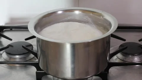 Milk boiling process.Milk boiling in saucepan kept on gas stove,not overflowing Stock Footage 159756519