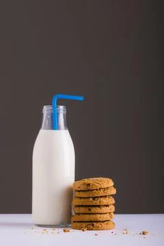 Milk bottle with straw by stack of cookies against gray background, copy space 스톡 사진
